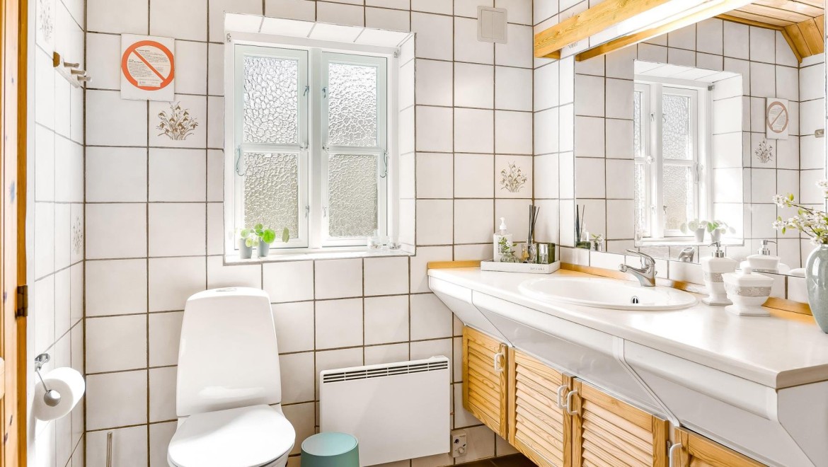 Kupatilo sa podnom WC šoljom, belim pločicama i drvenim nameštajem (© @triner2 and @strandparken3)